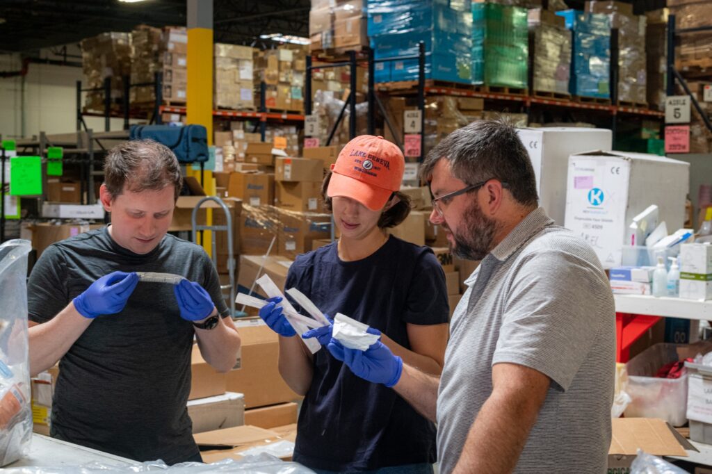 Volunteers sorting donated medical supplies in a Project C.U.R.E. warehouse. 