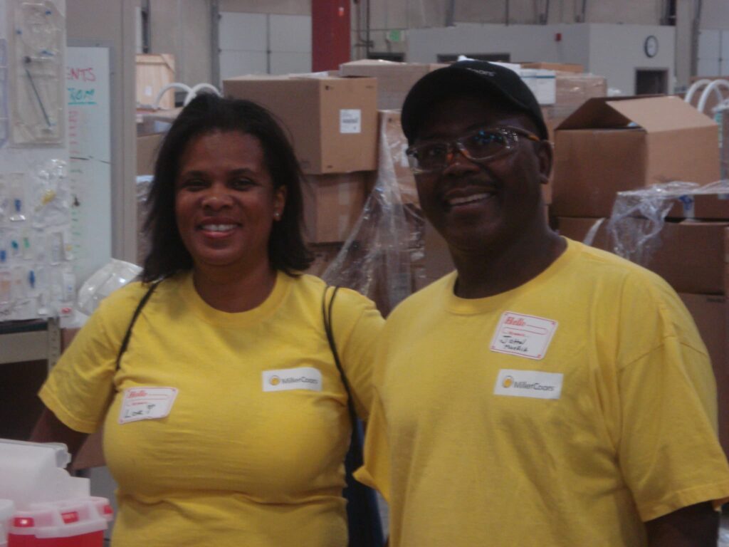 Lori Powell and John Muoria of Coors Brewing in Yellow t-shirts volunteering at the Project C.U.R.E. warehouse in Denver,