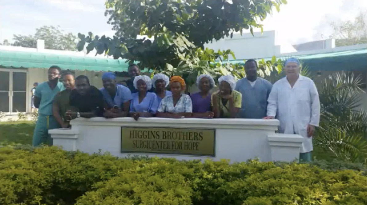 The hospital staff at Higgins Brother Surgical Center For Hope gathered together, smiling over the sign. 
