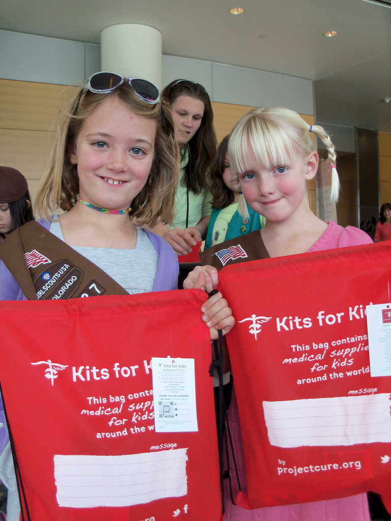 Colorado Girls Scouts hold up Project C.U.R.E. Kits for Kids bags at volunteer experience event