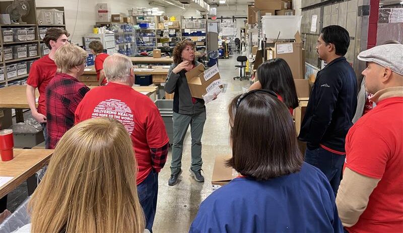 Biomed volunteer Julie Worger talks with a group of volunteers in the Phoenix warehouse of Project CURE