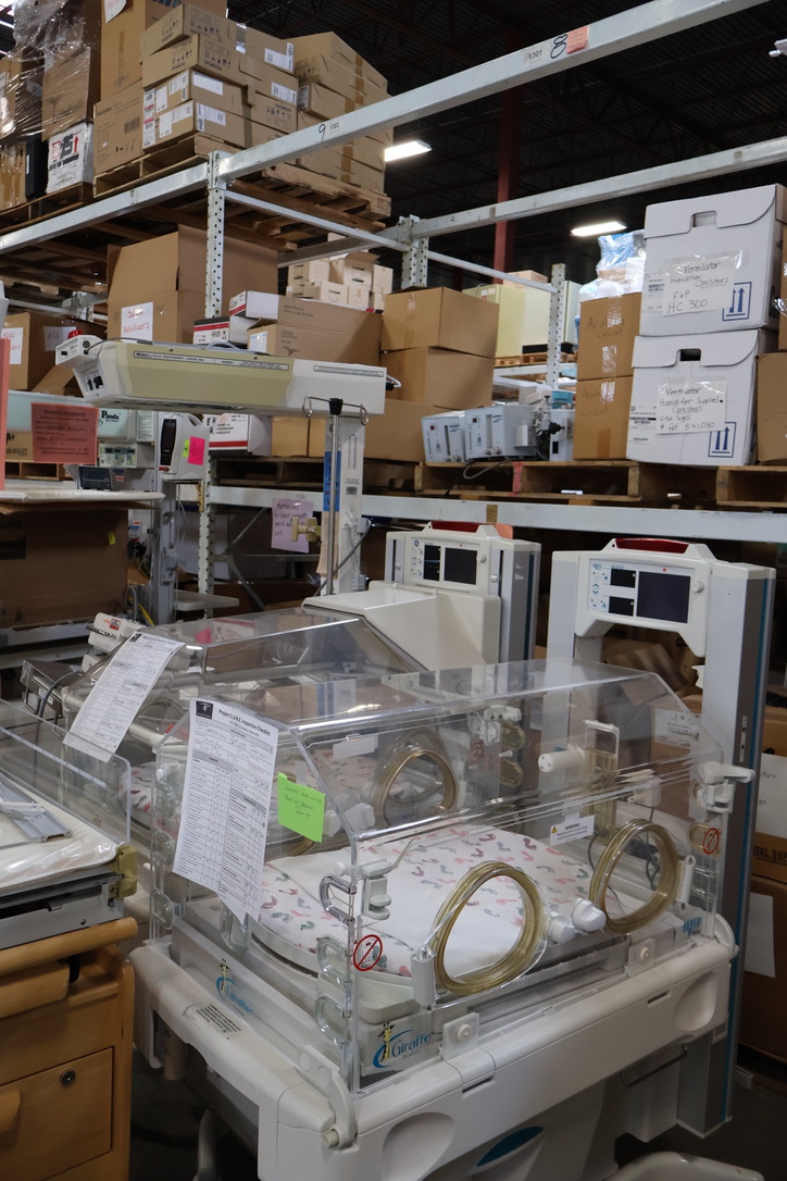 Neonatal incubators and donated medical equipment organized in a Project C.U.R.E. warehouse, ready for shipment to hospitals and clinics in underserved communities.