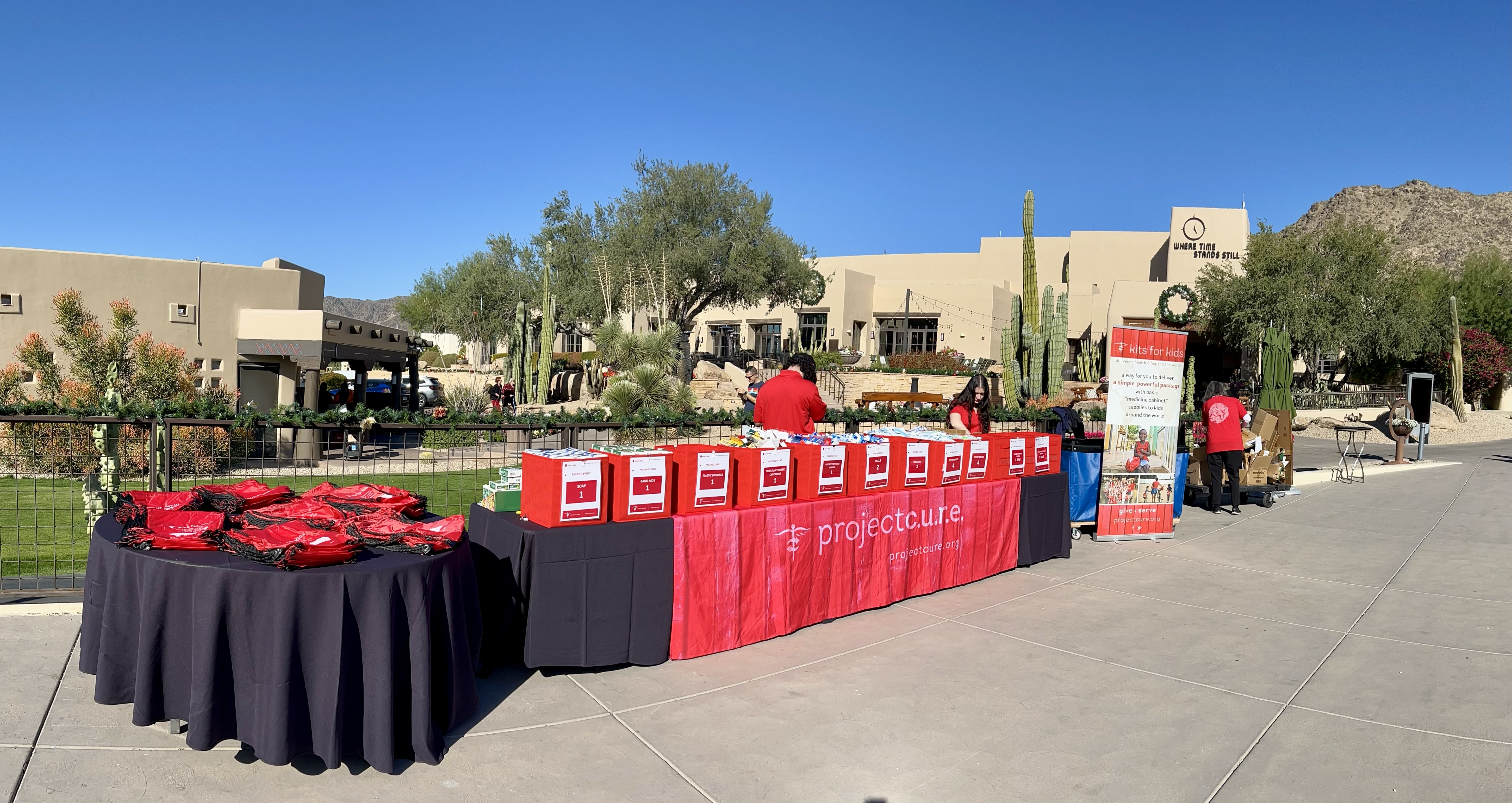 A table filled with medical and hygiene supplies, ready to be packed into red Kits for Kids backpacks.