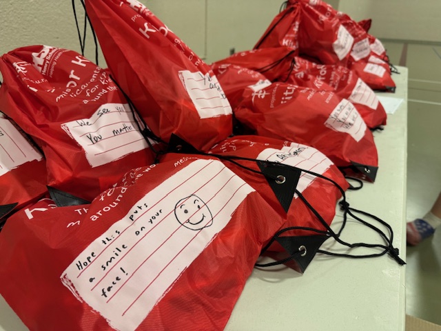 Pile of Kits for Kids that are packed ready to be shipped to underserved communities. Note on kit that says "Hope this puts a smile on your face!"