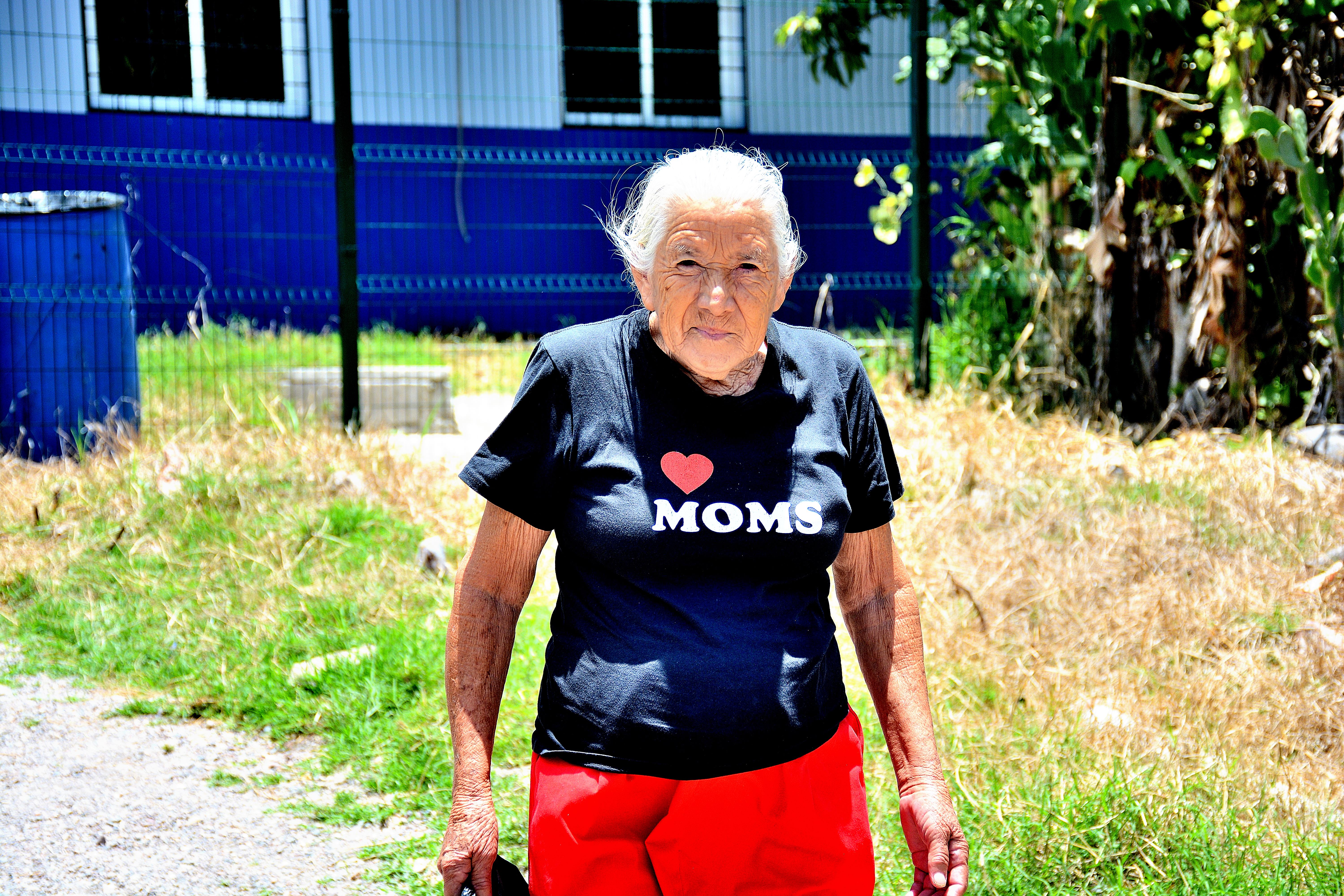Older woman leaving Project C.U.R.E. Clinic wearing "I Love Moms" shirt.