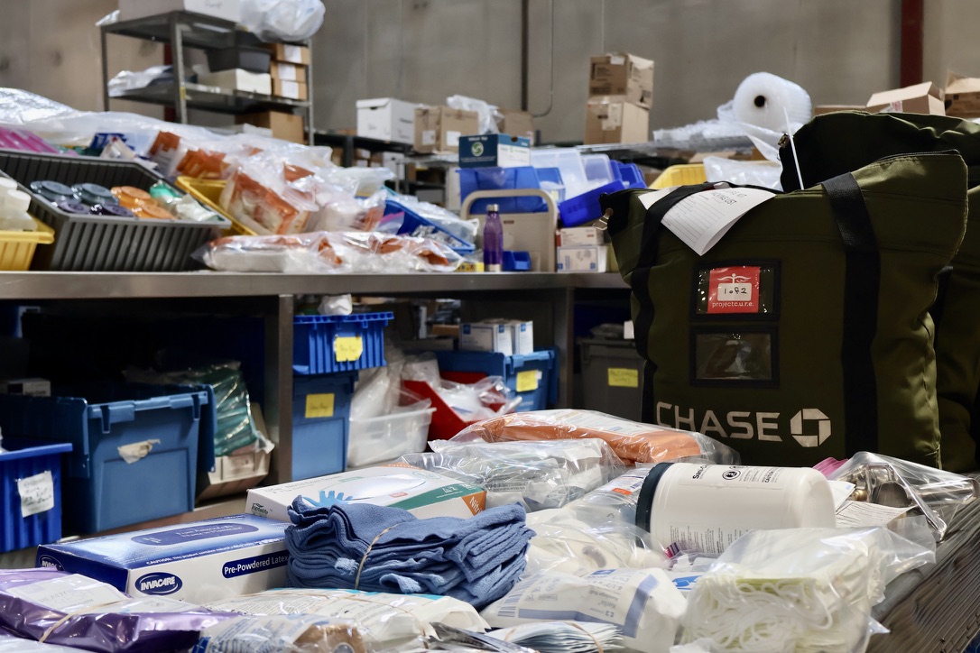 Medical supplies assembled for Project C.U.R.E. C.U.R.E. Kits, including gloves, gauze, masks, and hygiene items, organized in a warehouse for distribution to underserved communities.