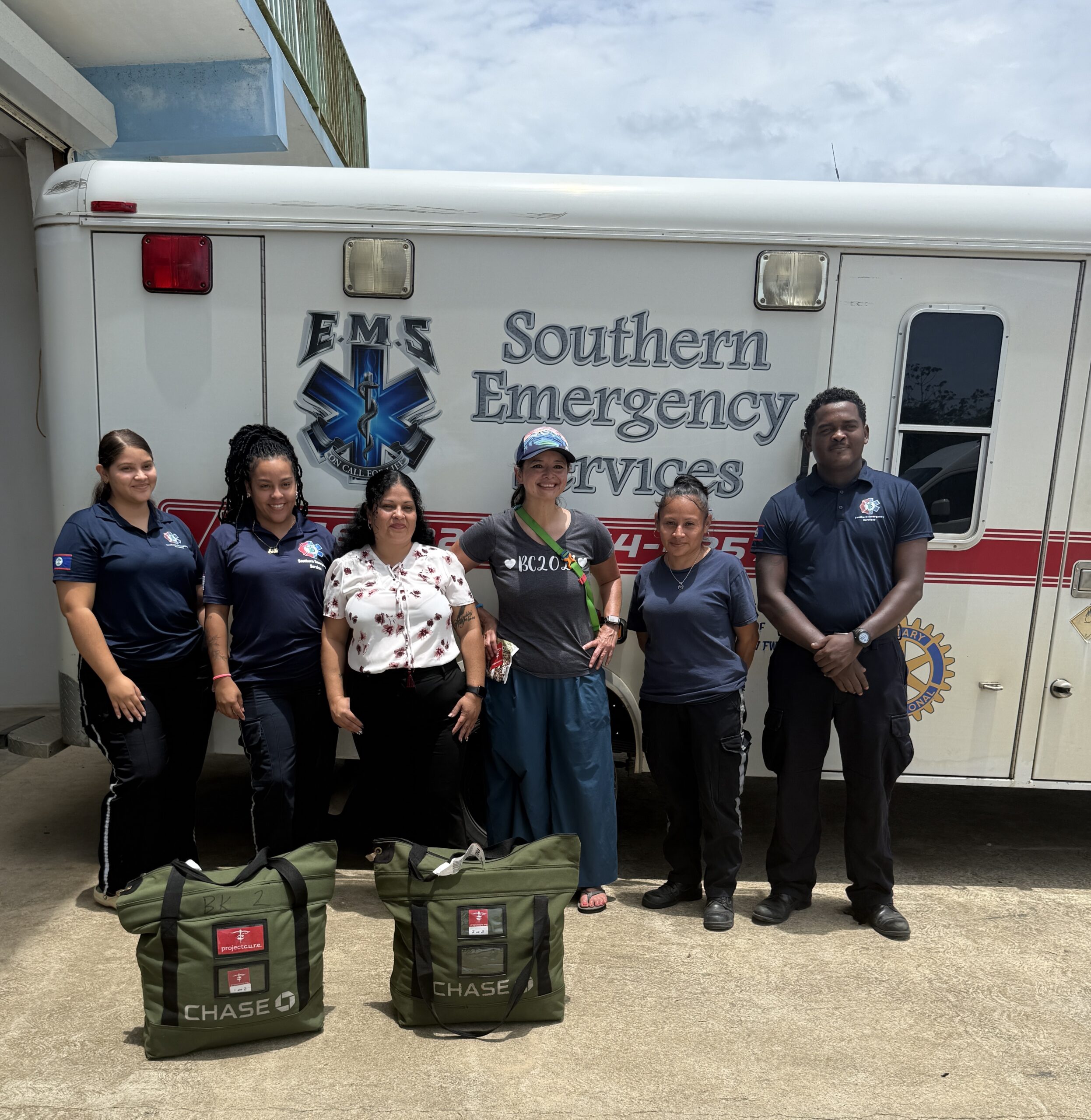 Project C.U.R.E. Volunteer delivering C.U.R.E. Kits to local Belize hospital standing in front of an ambulance