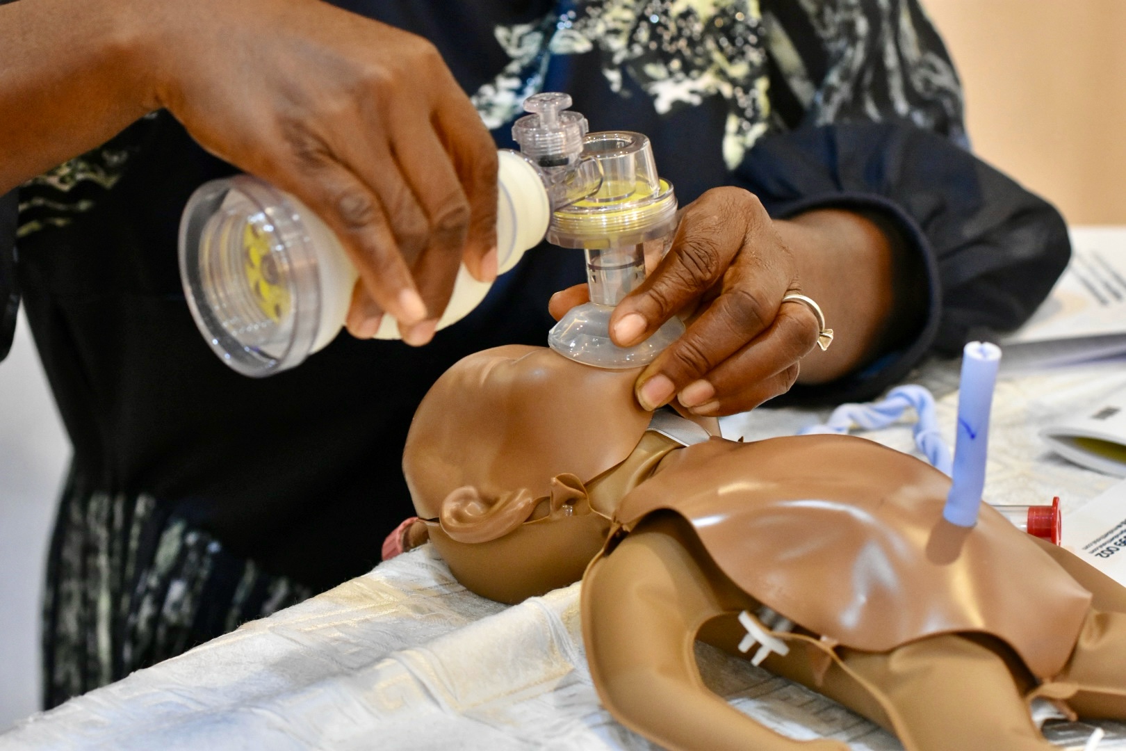 Newborn care training Ghana: healthcare worker practices ventilation using a resuscitation bag on a newborn simulation mannequin.
