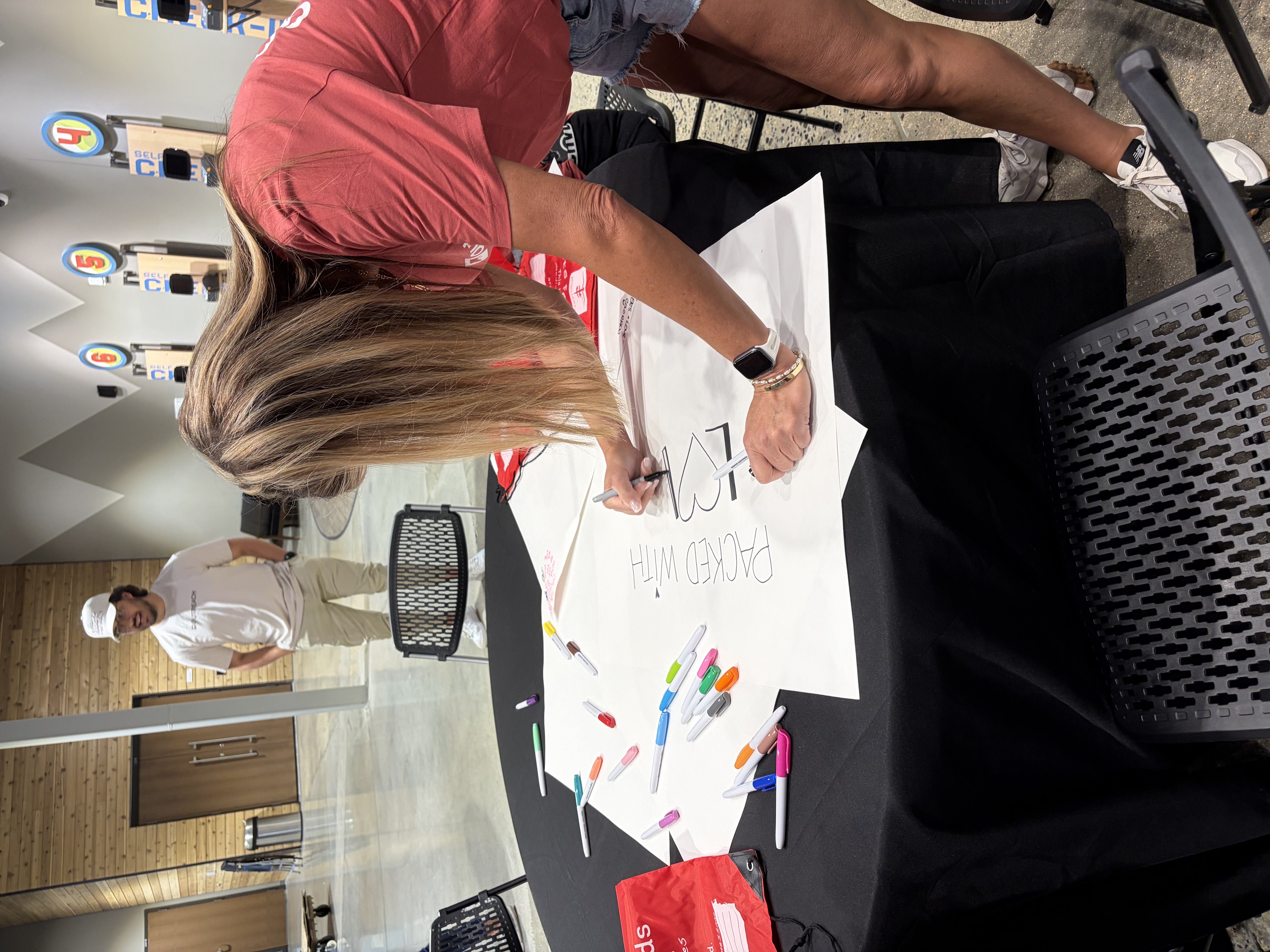 Red Rocks Church volunteer creating a "Packed with Love" sign for Kits for Kids