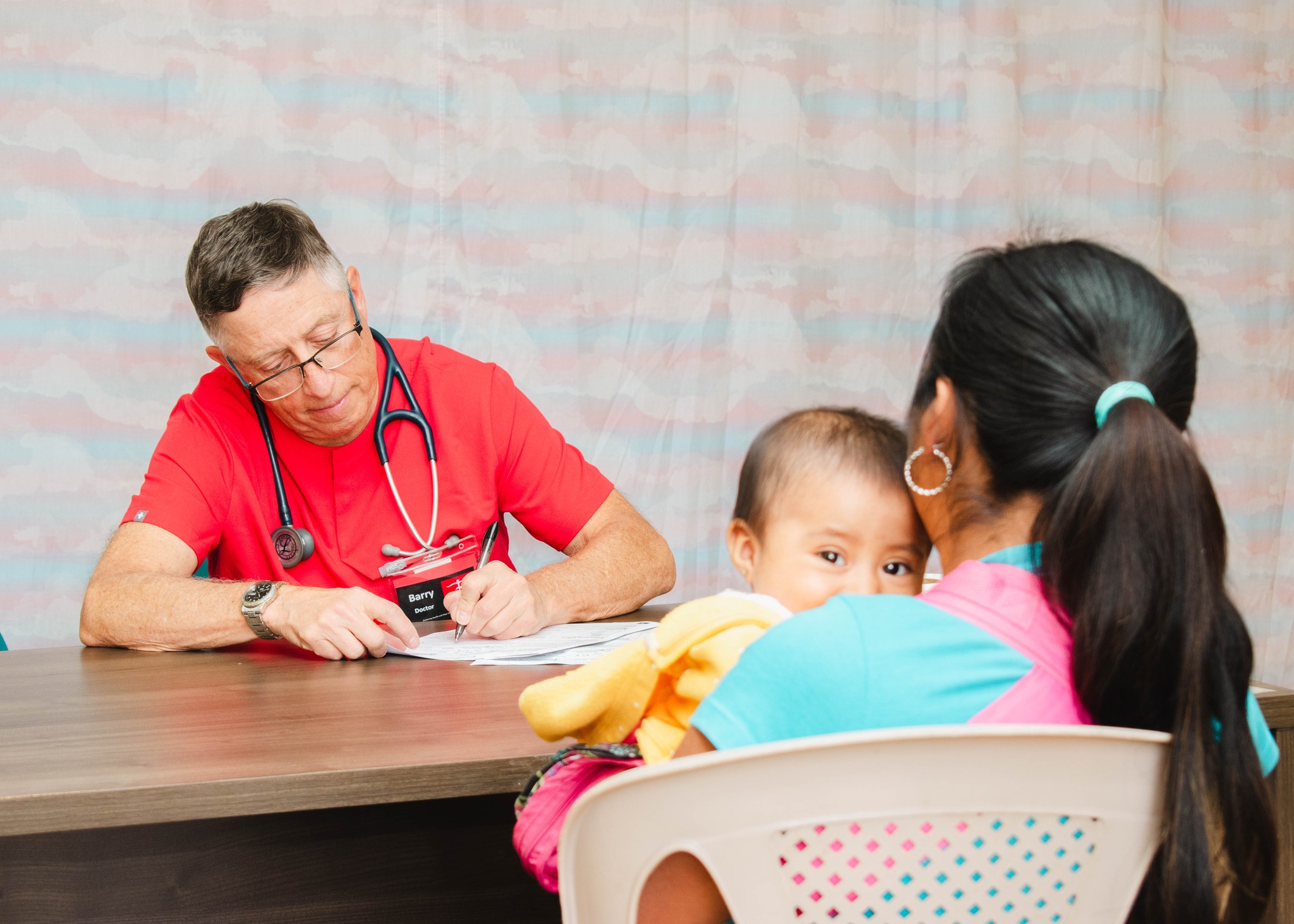 Volunteer physician consults with a mother and child, C.U.R.E. Clinic Guatemala