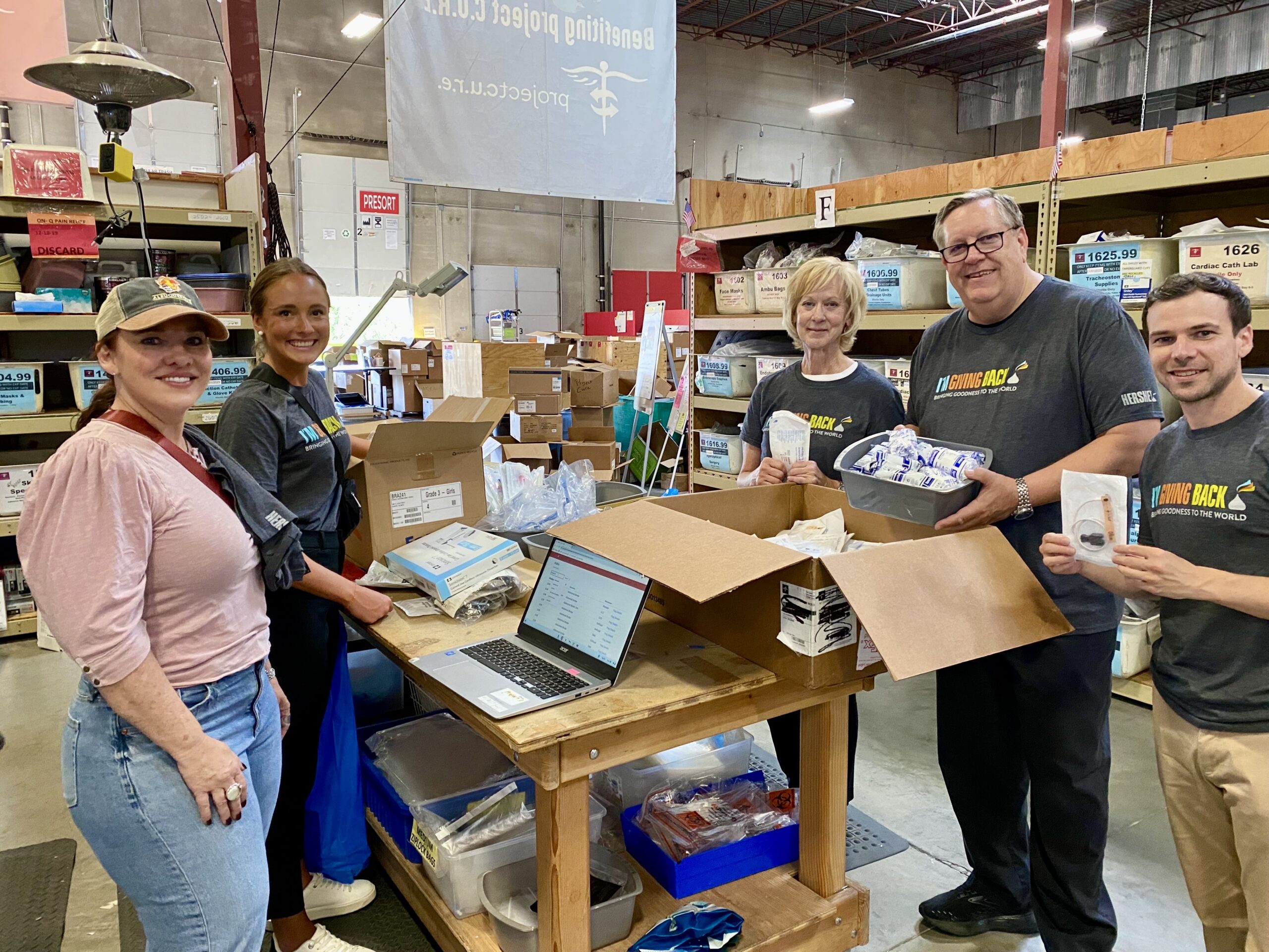 Corporate volunteering group sorting and packing donated medical supplies at a Project C.U.R.E. warehouse